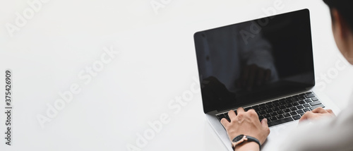 Man is using a computer laptop at the white simple workspace, Copy space concept.