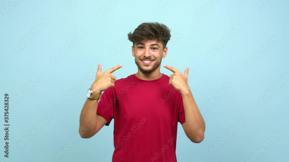 Young arab man smiles, pointing mouth, concept of perfect teeth, white teeth, has a cheerful and jovial attitude Young arab man smiles, pointing mouth, concept of perfect teeth, white teeth, has a cheerful and jovial attitude