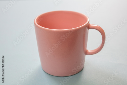 Coffee mug pink color on pastel blue background. Hot beverage cup mockup template
