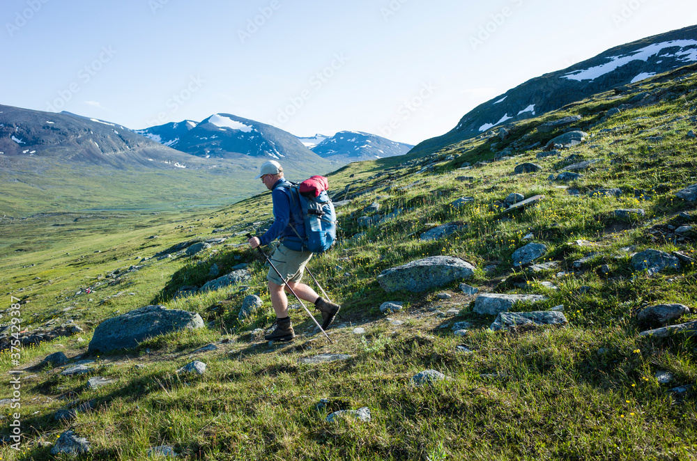Hiking in Swedish Lapland. Man traveler trekking alone Nordkalottruta Arctic Trail in northern Sweden. Mountain nature of Scandinavia in summer sunny day