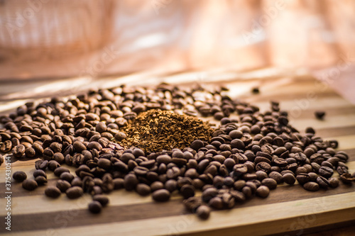 Roasted coffee beans are scattered on a wooden board and instant coffee is scattered inside.
