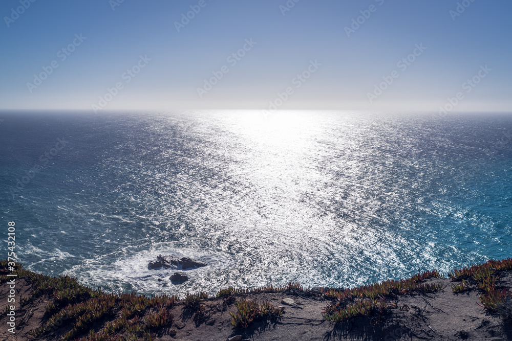 View across the coast to the ocean and horizon, sunshine in the water