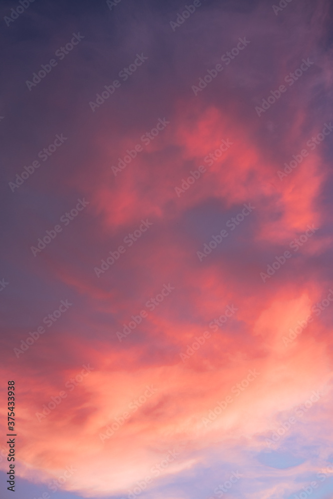 The sun illuminates the sky in such a way that it turns pink and orange. Beautiful summer sunset blue sky with pink clouds.
