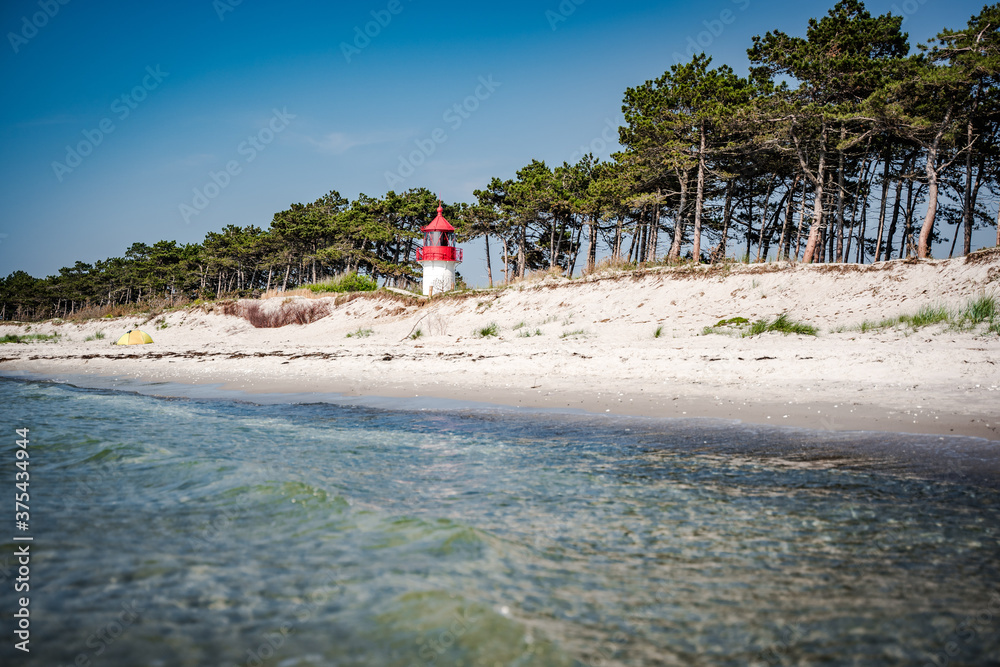 white sand beach with blue water an red white lighthouse white sand beach with blue water an red white lighthouse
