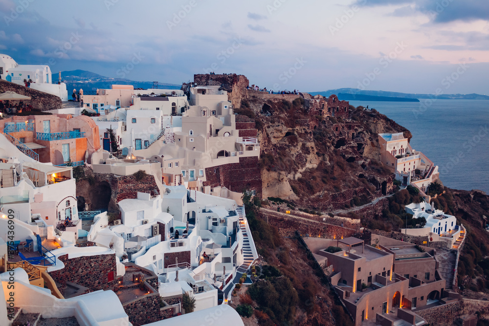 Santorini island Oia sunset landscape. Traditional white houses and castle ruins with sea view. Travel to Greece.