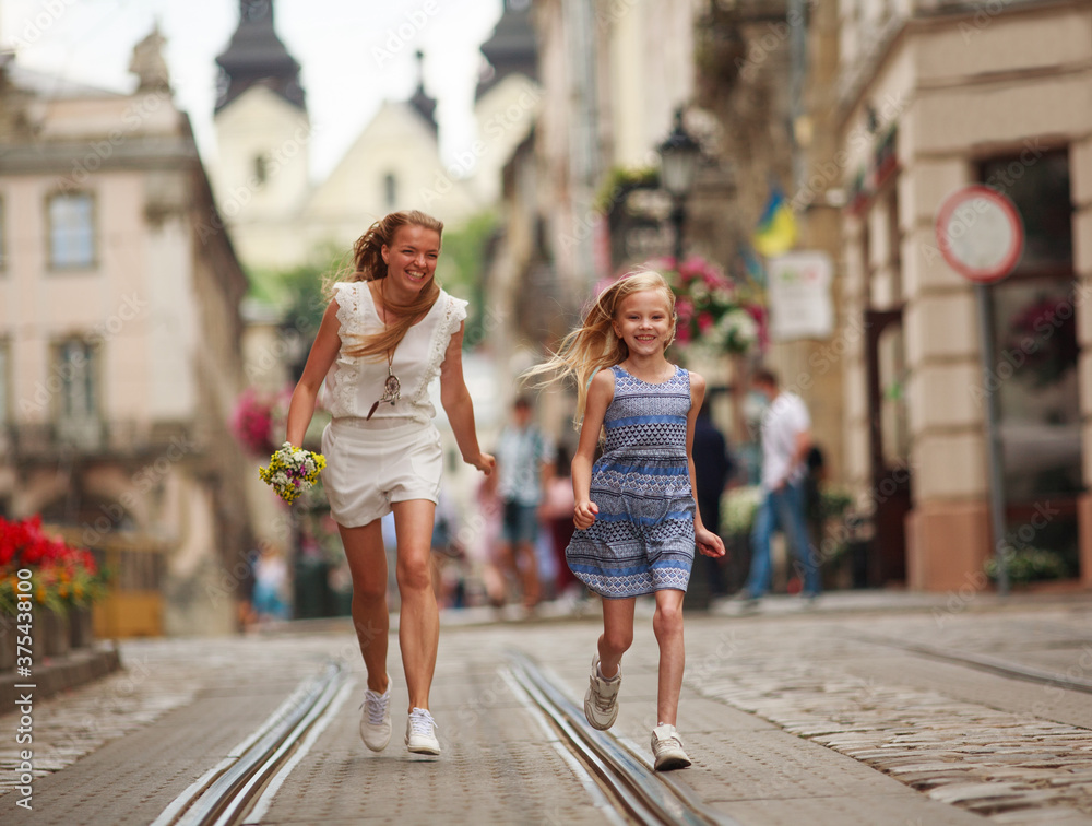 Mother and daughter have fun running on square of European tourist town Mother and daughter have fun running on square of European tourist town