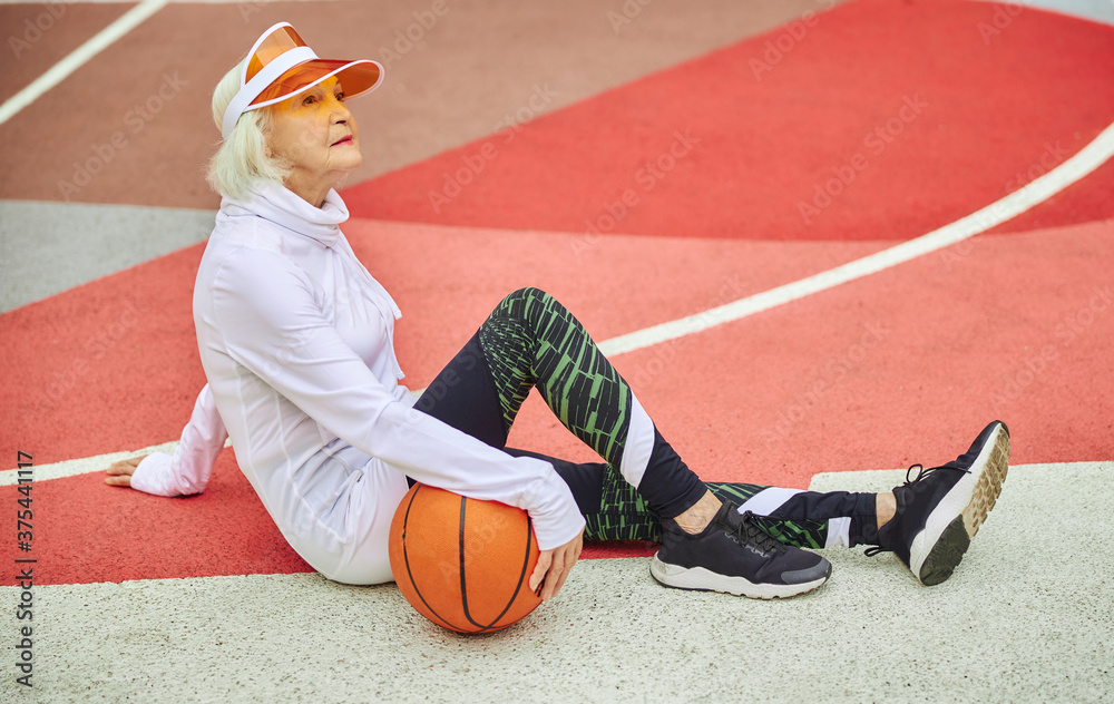 Naklejka premium Old cheerful lady on a colourfull square outdoors