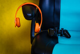 Concept Play online. Colored headphones and game controller on a gamer chair.