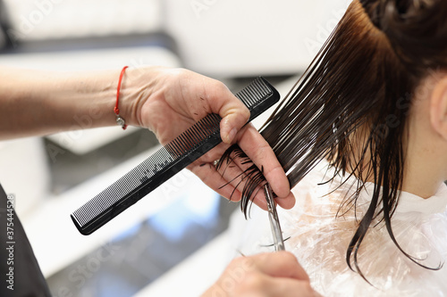 Master hairdresser cuts client's hair with scissors. Services beauty salon concept