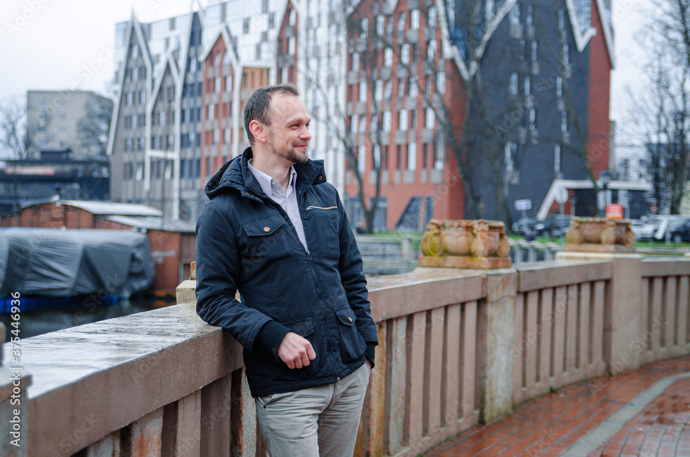 Handsome businessman freelancer in blue dark coat and beige trousers smiles Handsome businessman freelancer in blue dark coat and beige trousers smiles