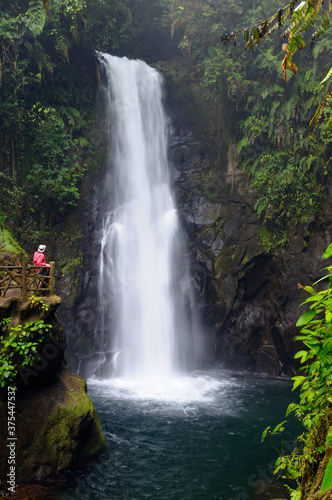 Wet tourist watching a rainforest waterfall in Costa Rica