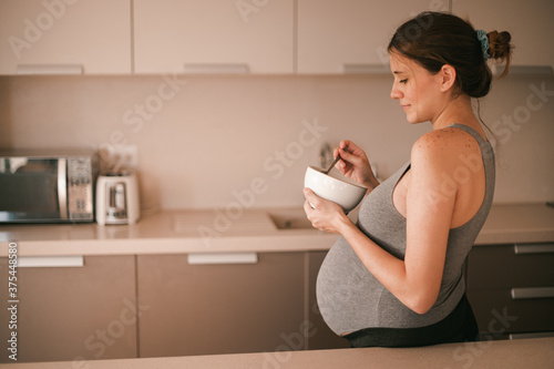 Pregnancy young woman in kitchen (ID: 375448580)