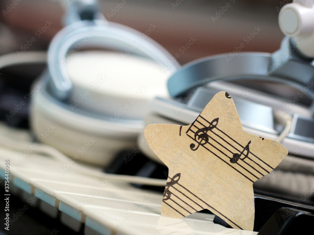 A star of paper music notes and white headphones on the piano. A star of paper music notes and white headphones on the piano.