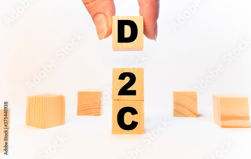 The hand puts the cube block with the inscription D2C. Business to business concept background.
