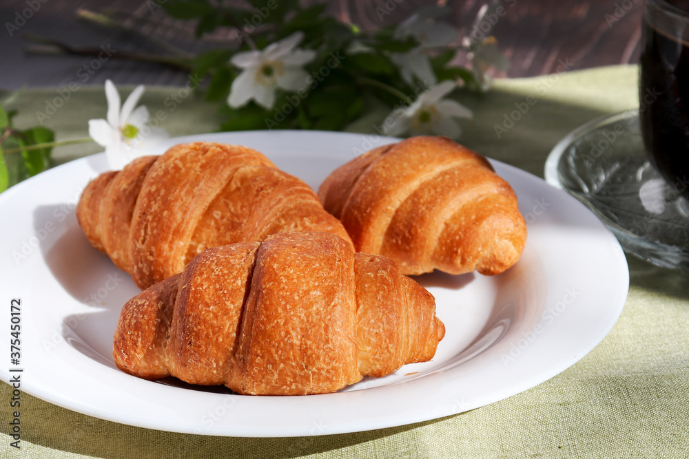 Fresh baked croissants lie on a white plate. Warm fresh croissants and butter rolls. French and American croissants and pastries are popular all over the world for breakfast Fresh baked croissants lie on a white plate. Warm fresh croissants and butter rolls. French and American croissants and pastries are popular all over the world for breakfast