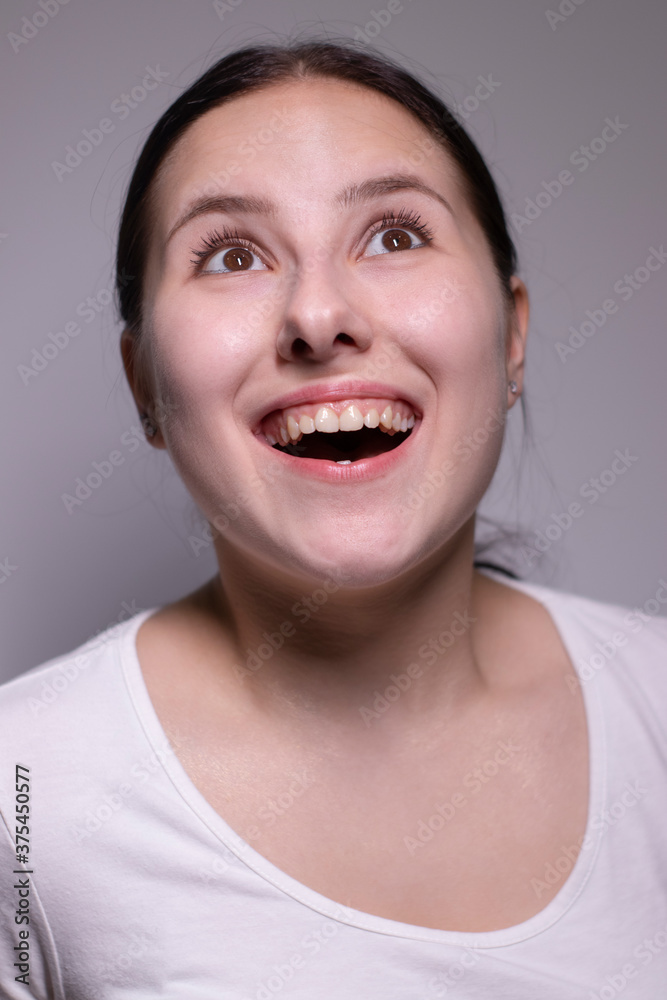 Indoor portrait of Beautiful smiling brunette with clean skin, natural make-up. smiling cheerfully, feeling happy and carefree. cosmetic concept. young model with beautiful smile on grey background