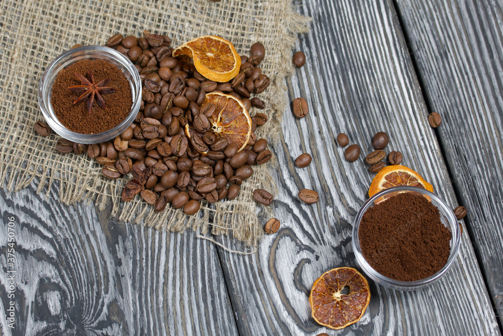 Coffee beans on coarse linen. Ground coffee in containers and spices. On a surface of brushed pine boards painted black and white. Coffee beans on coarse linen. Ground coffee in containers and spices. On a surface of brushed pine boards painted black and white.