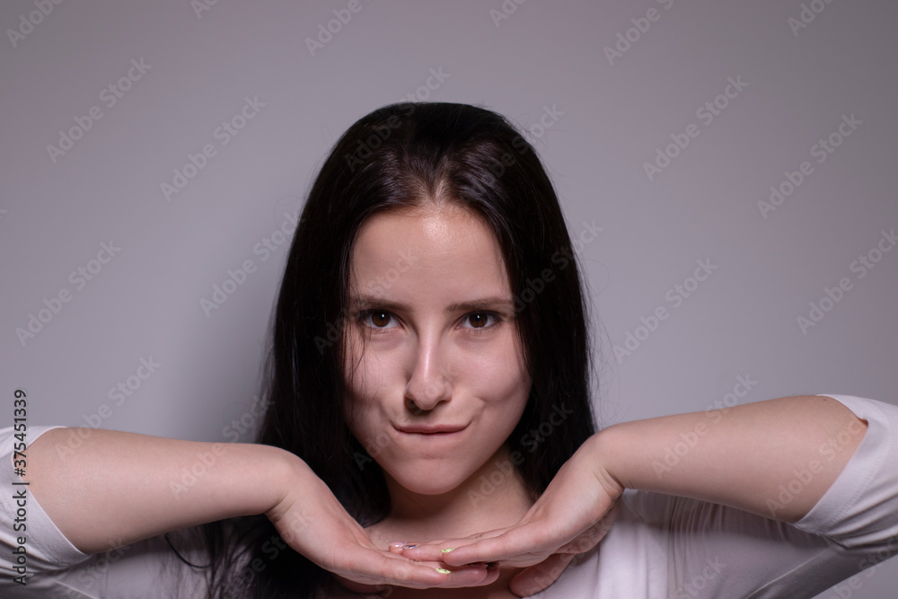 Indoor portrait of Beautiful smiling brunette with clean skin, natural make-up. smiling cheerfully, feeling happy and carefree. cosmetic concept. young model with beautiful smile on grey background Indoor portrait of Beautiful smiling brunette with clean skin, natural make-up. smiling cheerfully, feeling happy and carefree. cosmetic concept. young model with beautiful smile on grey background