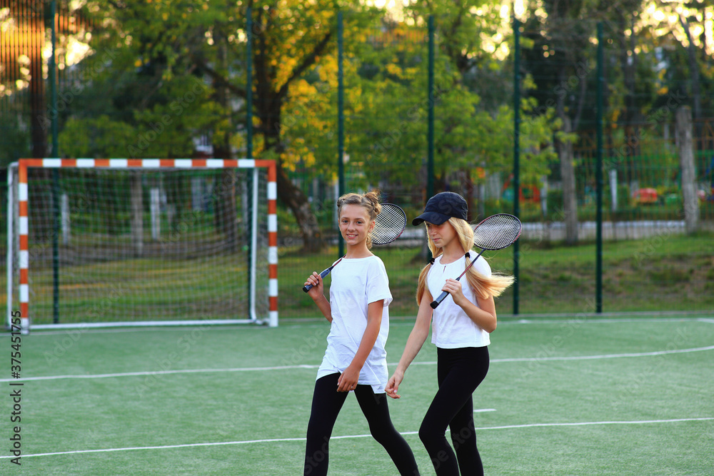 Two girls after lessons go in for tennis on the playground. Two girls after lessons go in for tennis on the playground.