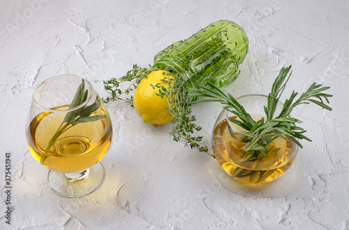 Rosemary herbal tea in glass cups, lemon with thyme. White textured cement background photo