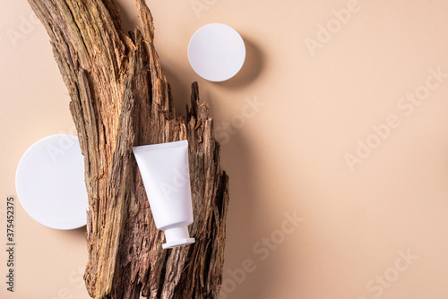 White unlabelled cosmetic bottle on dry wooden bark background. Skin care, organic body treatment, skin nutrition concept. Eco friendly product. Organic cosmetics. Moistening, dry skin concept photo