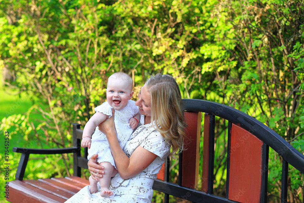 Fototapeta premium Young family with a child in the park. Portrait of mom and daughter outdoors