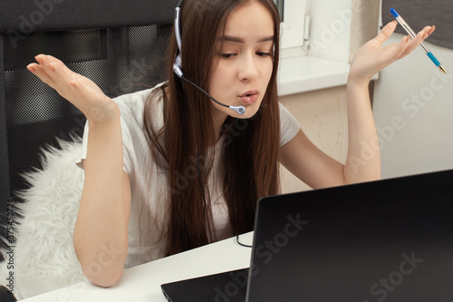 The difficulties of online education. Webinar. Student at home with a microphone in headphones indignant in front of the monitor photo