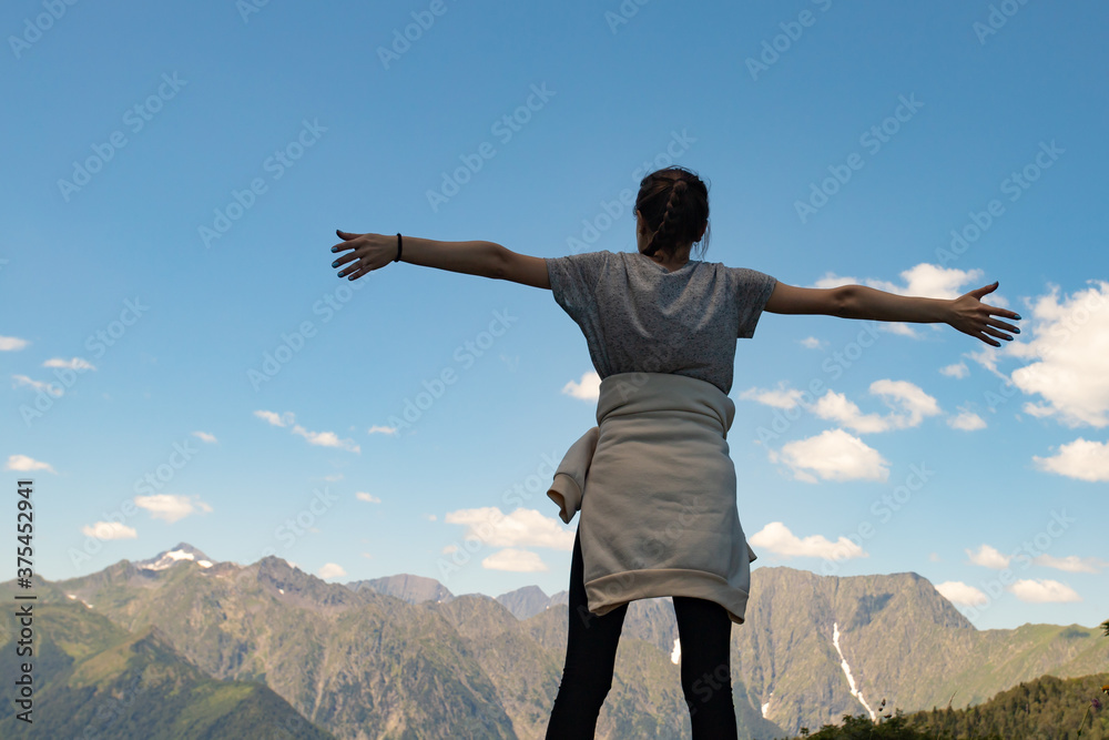Travel, adventure and trekking by Hiking in the mountains. A girl stands on top of a mountain hands up