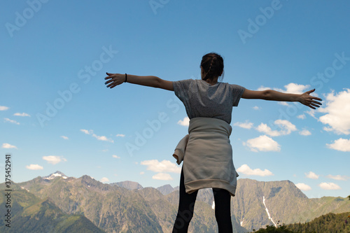 Travel, adventure and trekking by Hiking in the mountains. A girl stands on top of a mountain hands up