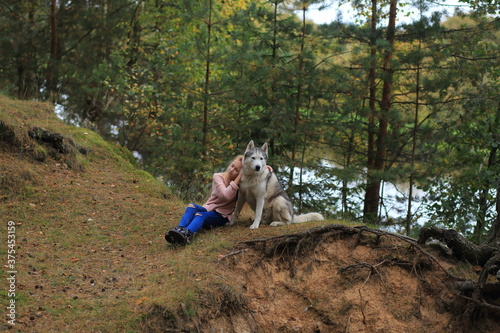 A girl with a husky walks in the forest.