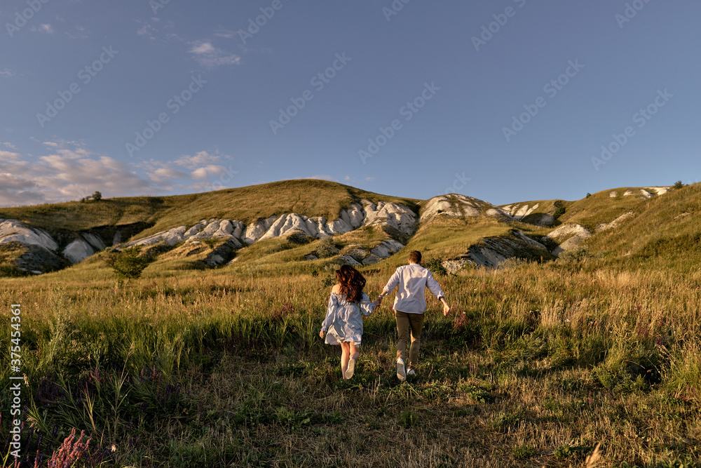 A couple in love runs across the field in sunset light. Lifestyle - concept.