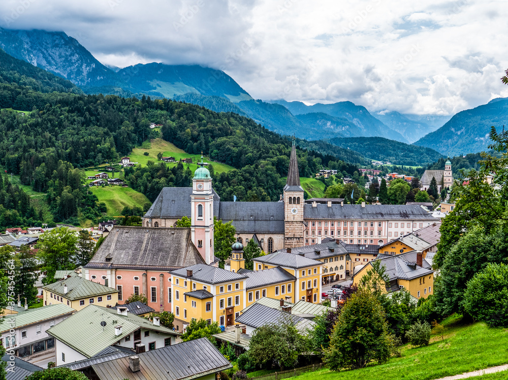 Berchtesgaden Zentrum mit Schloss uns Stiftskirche eingebettet in eine Berglamdschaft bei wolkenverhangenem Himmel