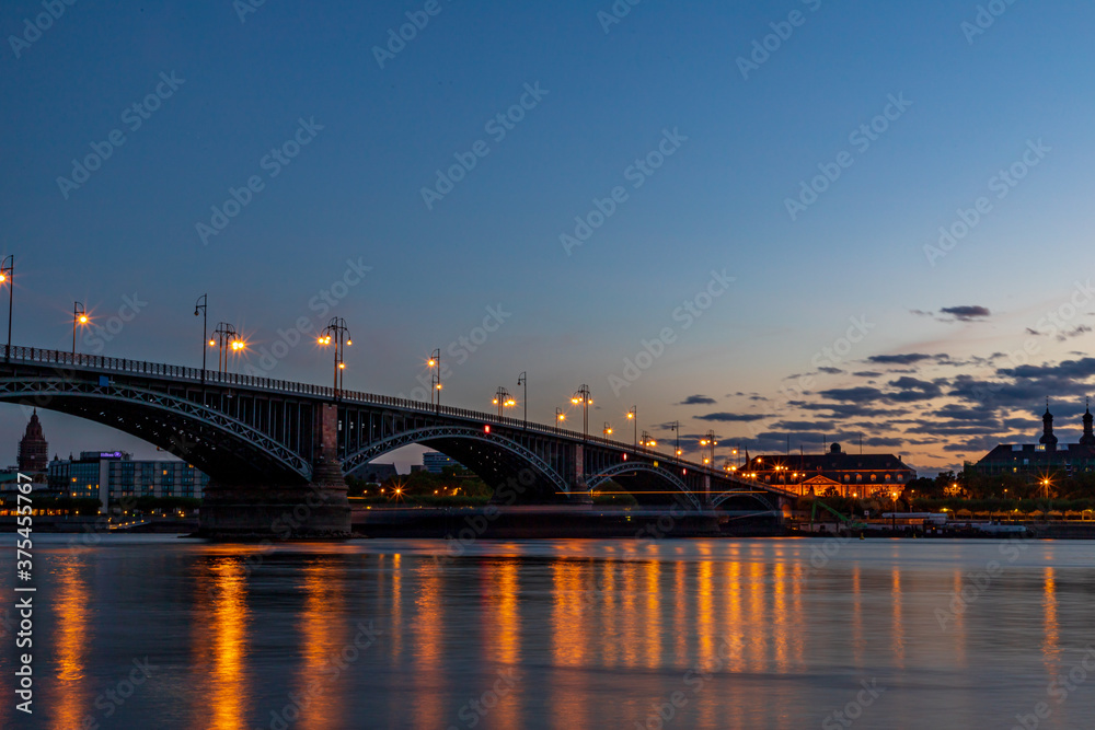 The illuminated Theodor Heuss Bridge that crosses the Rhine between Mainz and Wiesbaden at night. In the background the silhouette of Mainz