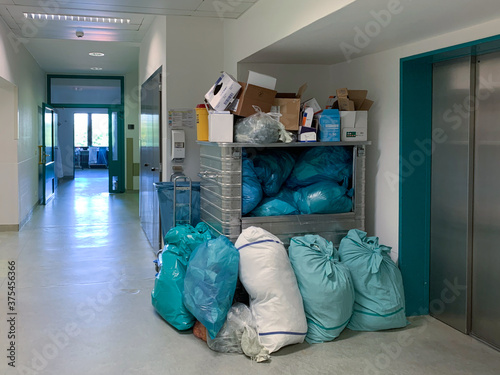 in a corner of a hospital corridor different garbage bags are piled up