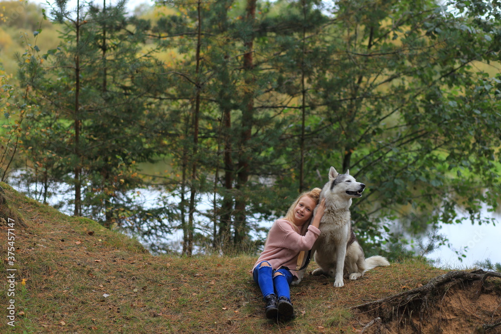 A girl with a husky walks in the forest. A girl with a husky walks in the forest.