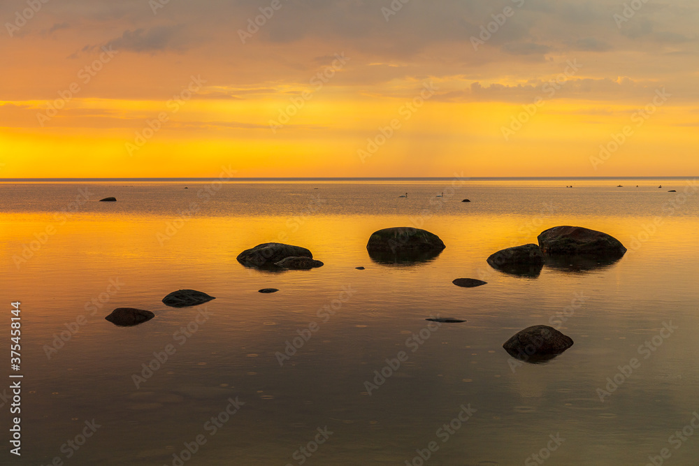 Orange sunset rocky shore of Baltic sea.
