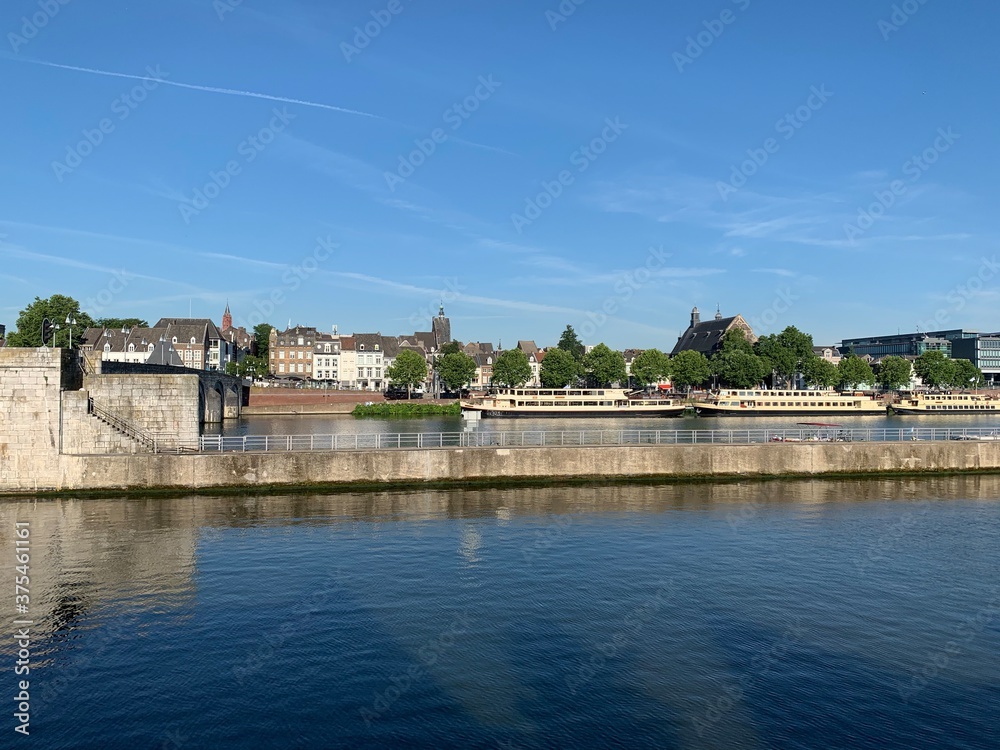 City skyline with boats at Meuse (Maas) river and Augustijnen church in Maastricht, the Netherlands. 