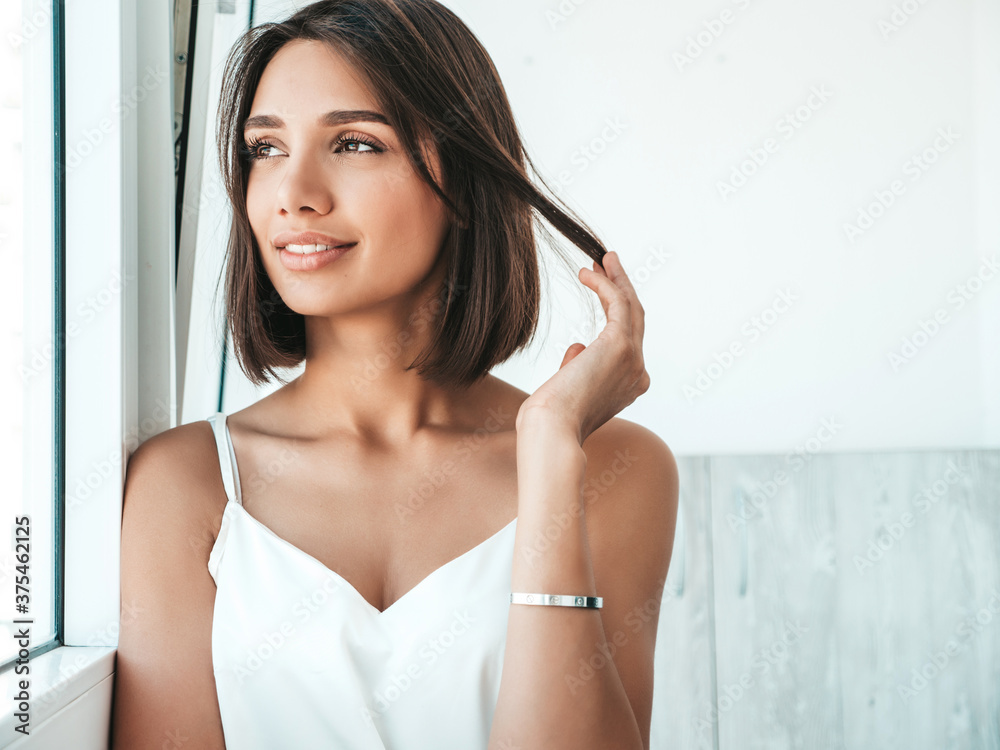 Portrait of beautiful woman dressed in white pajamas. Sexy carefree model enjoying her morning at balcony. She dreams about something and looking out the window. Female in her thoughts Portrait of beautiful woman dressed in white pajamas. Sexy carefree model enjoying her morning at balcony. She dreams about something and looking out the window. Female in her thoughts