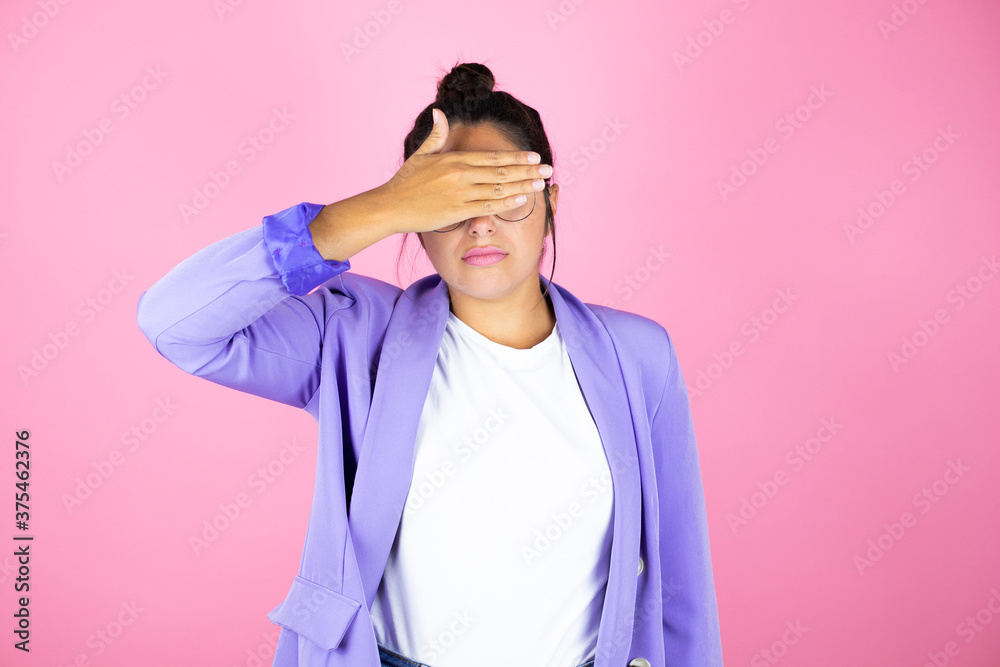 Young beautiful business woman over isolated pink background serious and covering her eyes with her hand Young beautiful business woman over isolated pink background serious and covering her eyes with her hand