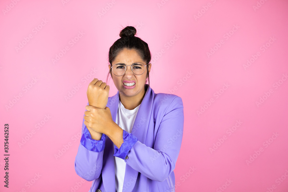 Young beautiful business woman over isolated pink background suffering pain on hands and fingers, arthritis inflammation Young beautiful business woman over isolated pink background suffering pain on hands and fingers, arthritis inflammation