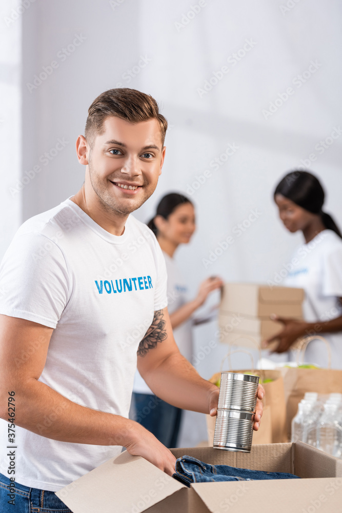 Selective focus of volunteer holding tin cans near package in charity center