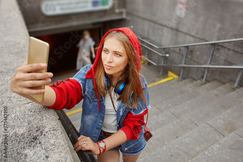 Young woman takes selfie near subway enter.