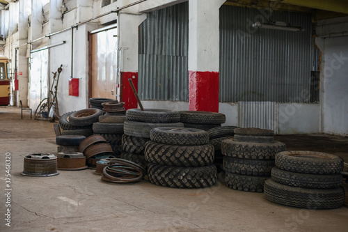 A pile of different tires in a big old industrial bus garage © Dmitriy D