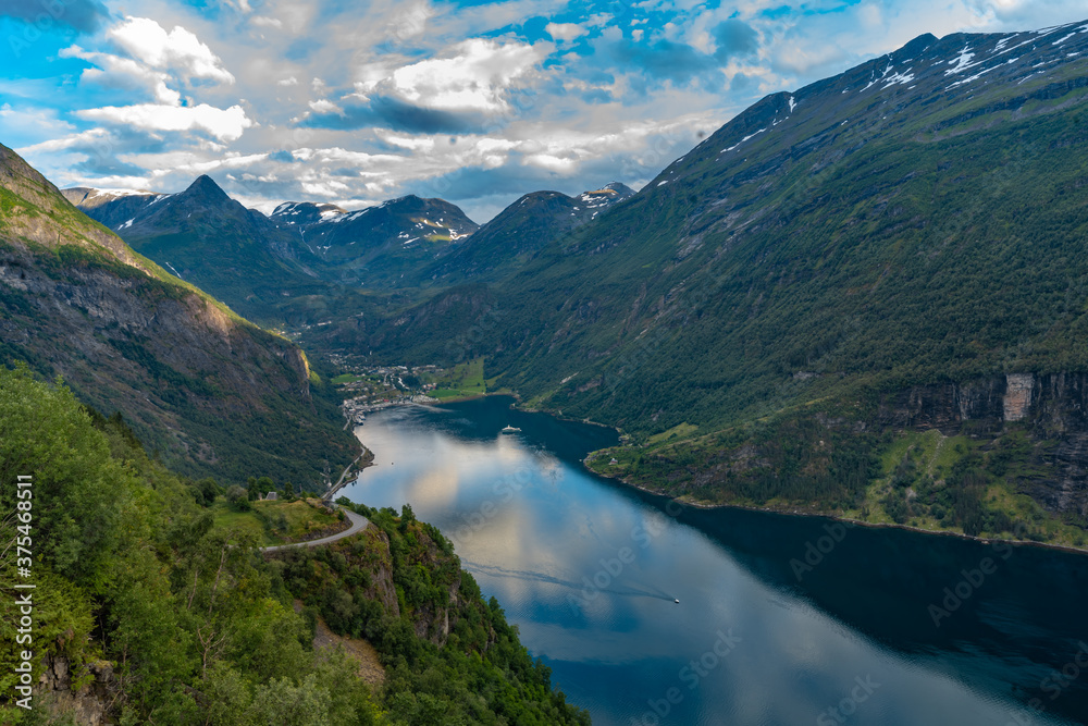 Scenic view of the Geiranger Fjord, Norway. A spectacular, narrow finger of the Sunnylvsfjorden, a branch of the Storfjorden. Geiranger village is located at the end of the fjord Scenic view of the Geiranger Fjord, Norway. A spectacular, narrow finger of the Sunnylvsfjorden, a branch of the Storfjorden. Geiranger village is located at the end of the fjord