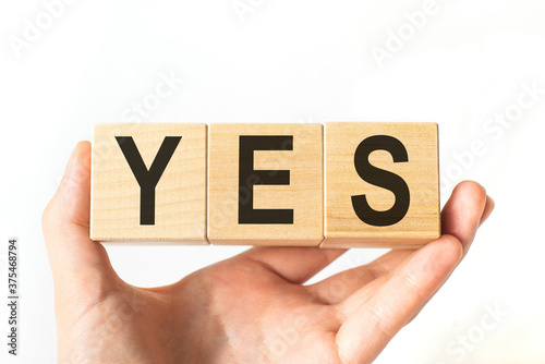 Hand holds wooden cubes with letters YES. Business concept image.