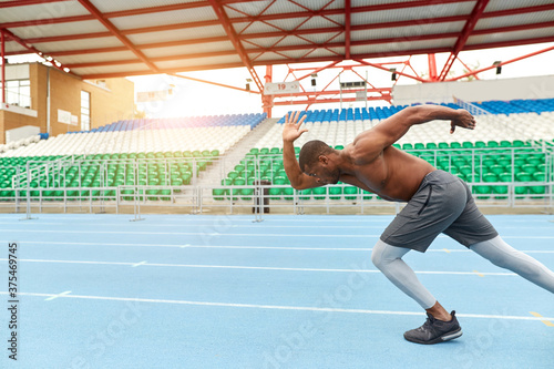 shirtless man running in the track., side view photo, copy space ,man working out at the stadium, challenge