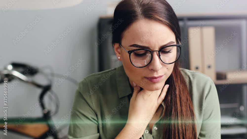 Close up of beautiful woman working on laptop in modern office. Tired girl sitting at work touches her neck feeling sore throat. Close up of beautiful woman working on laptop in modern office. Tired girl sitting at work touches her neck feeling sore throat.