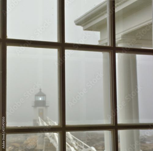 Foggy day at Marshall Point in Port Clyde Maine. Historic Marshall Point Light and walkway viewed from window inside lighthouse. photo