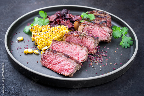 Barbecue dry aged wagyu roast beef steak with corn and vegetable chips offered as close-up on a modern design plate