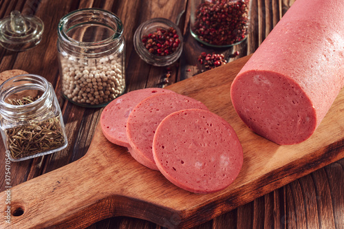 Sliced mortadella on a wood cutting board with spices photo